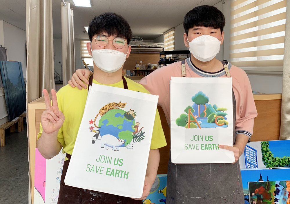 (왼쪽부터) 밀알복지재단 ‘브릿지온 아르떼’ 최석원 작가, 김승현 작가가 다회용 쇼핑백을 들고 기념촬영을 하고 있다..jpg